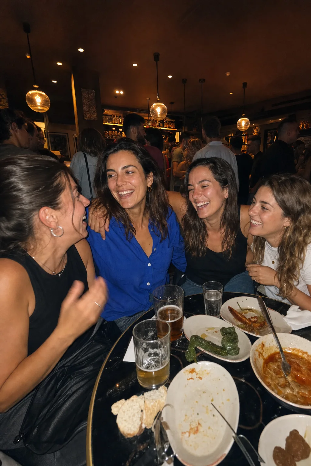 Lucía laughing with friends at a crowded Madrid tapas bar
